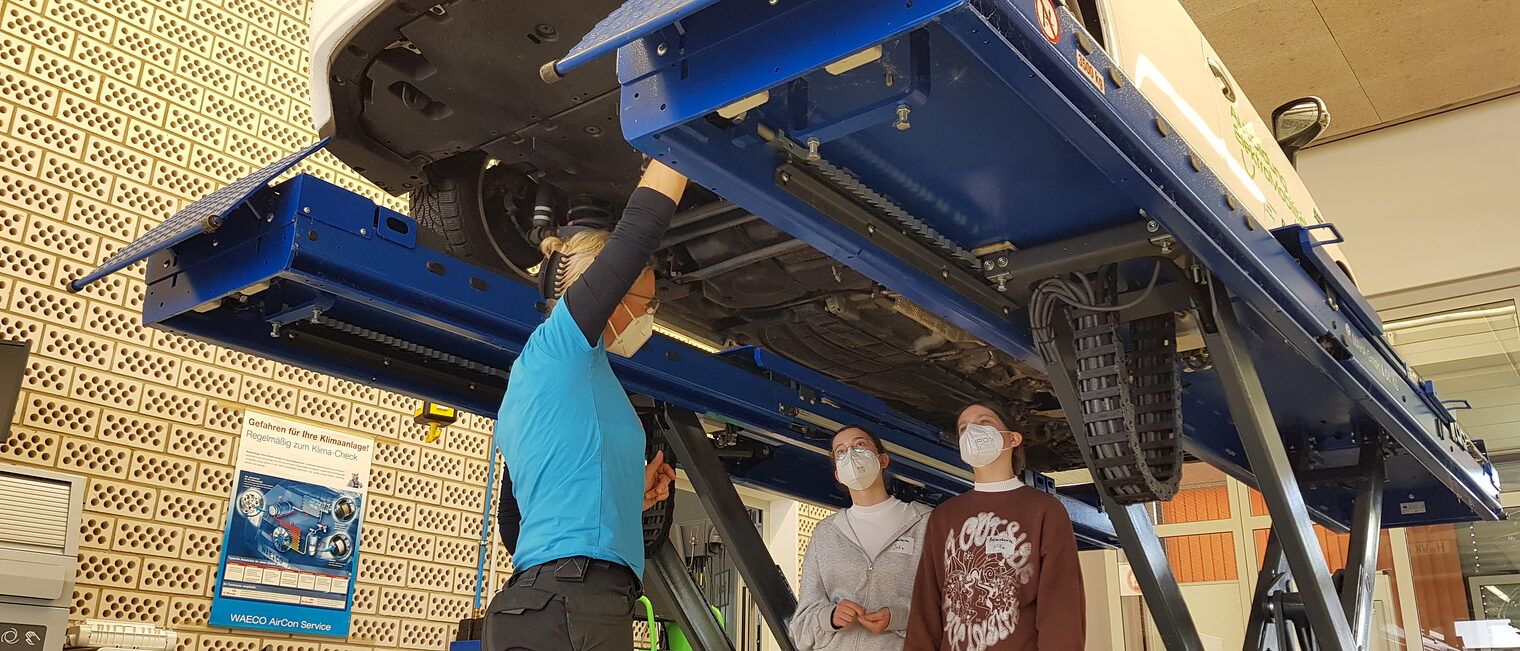 Nicht nur unter die Haube, sondern gleich unters ganze Auto schauen: Katja Jandrey zeigt zwei Schülerinnen beim Girls' Day auf dem Campus Handwerk, wie ein Auto aufgebaut ist.