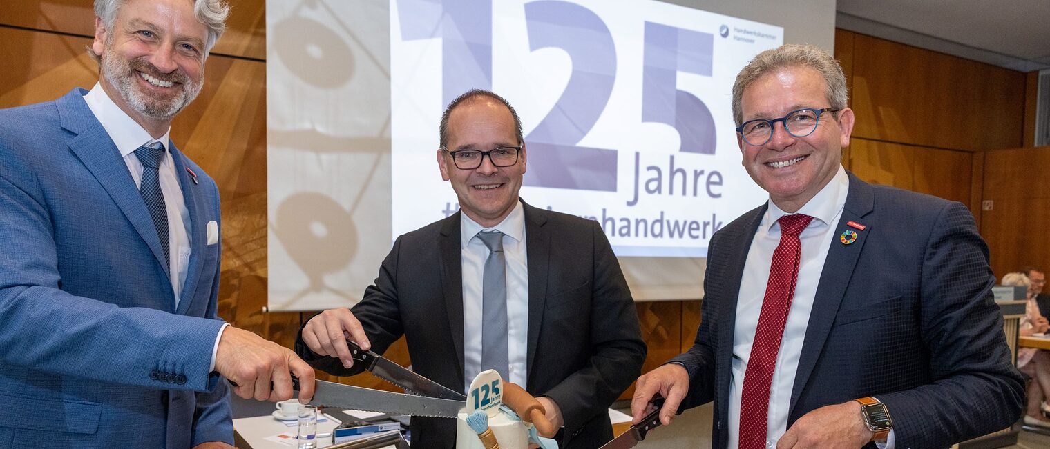 Peter Karst, Wirtschaftsminster Grant Hendrik Tonne und Kammerpräsident Thomas Gehre (v.l.n.r.) machen den Tortenanschnitt.