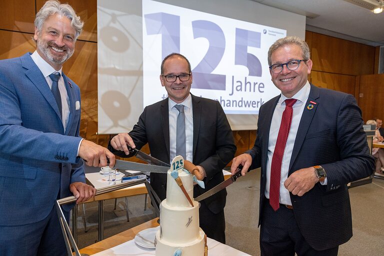 Peter Karst, Wirtschaftsminster Grant Hendrik Tonne und Kammerpräsident Thomas Gehre (v.l.n.r.) machen den Tortenanschnitt. 