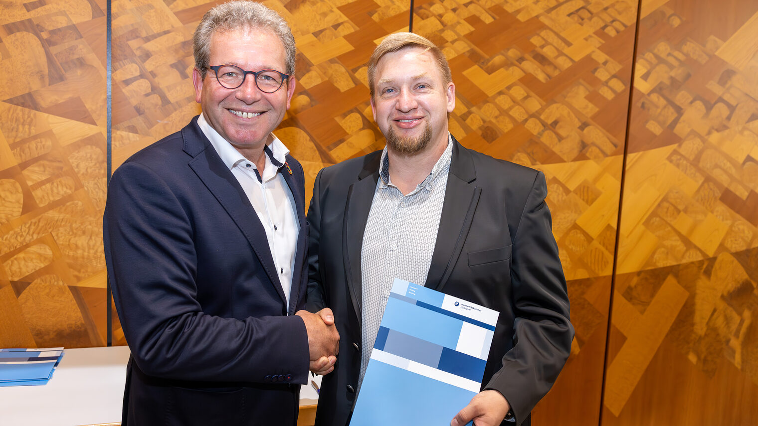 Präsident Thomas Gehre überreicht die Urkunde an den zufiedenen Absolventen.