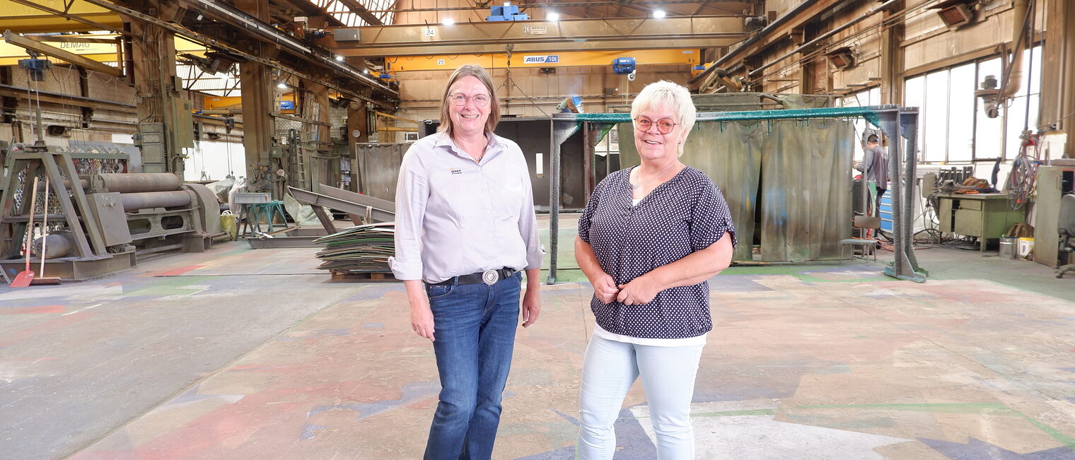 STICHWEH-Geschäftsführerin Anja Gröhlich und Ute Olthoff, Mitarbeiterin Administration, stehen in der großen Werkstatthalle.