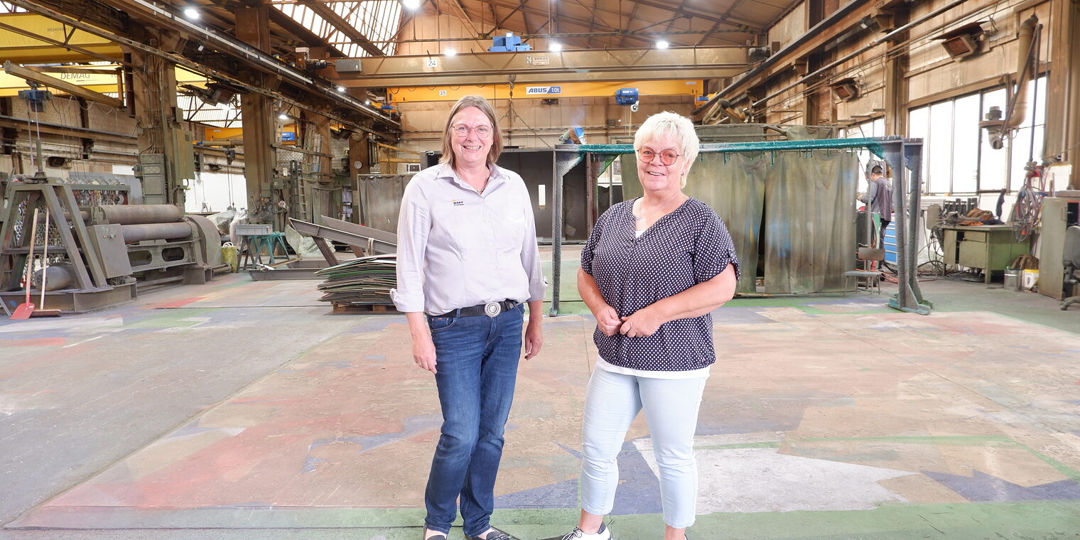 STICHWEH-Geschäftsführerin Anja Gröhlich und Ute Olthoff, Mitarbeiterin Administration, stehen in der großen Werkstatthalle.