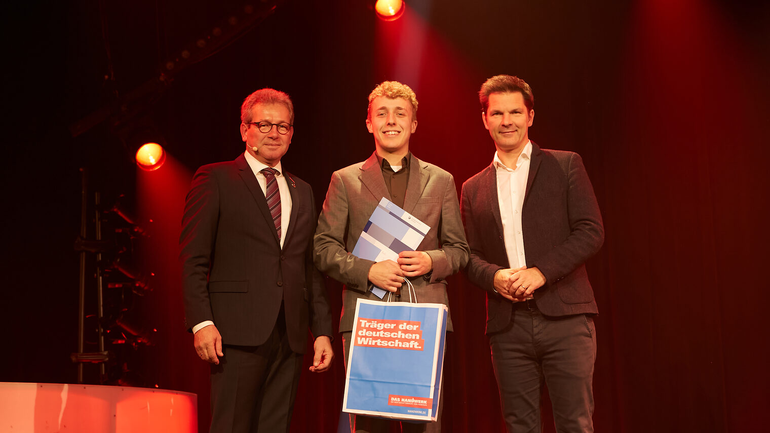 Jonas Cohrs mit Kammerpräsident Thomas Gehre (li.) und Regionspräsident Steffen Krach (re.) auf der Bühne im GOP Hannover.