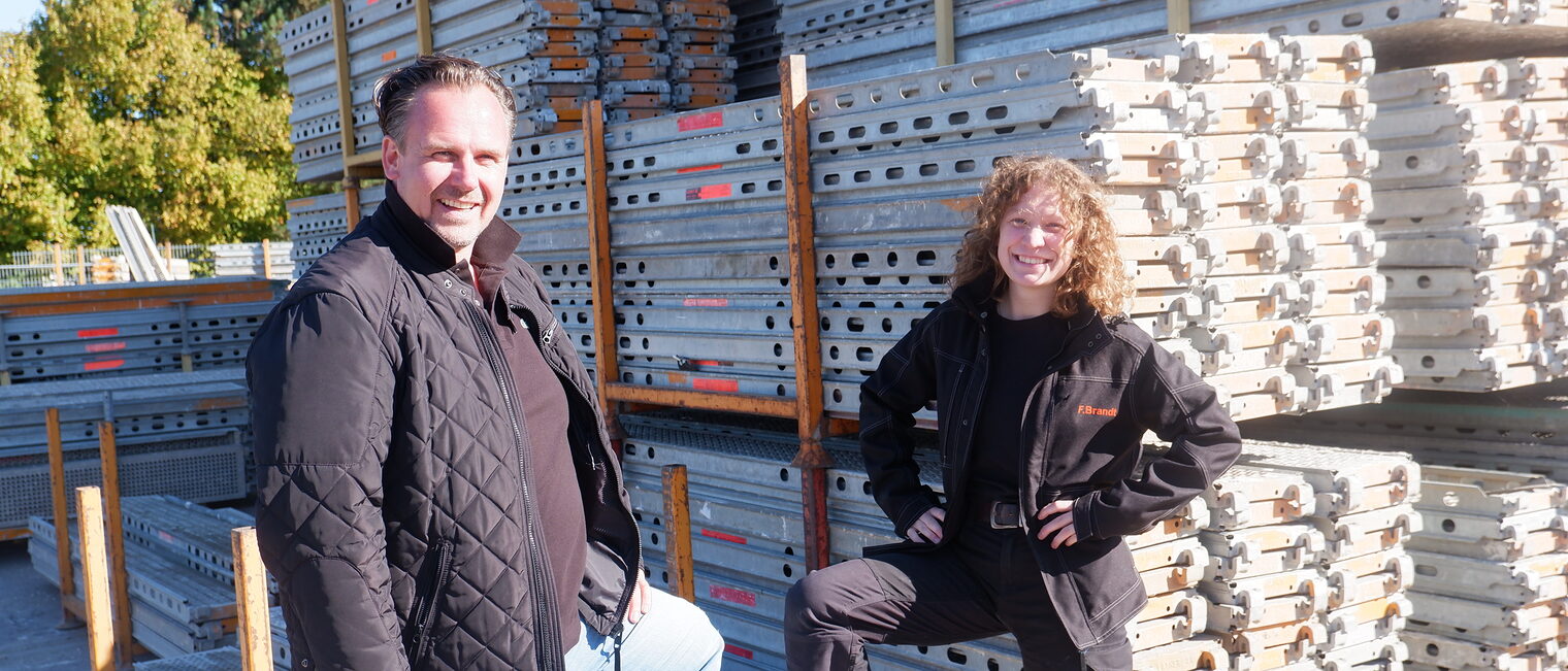 Ausbilder und Auszubildende stehen draußen vor einem 