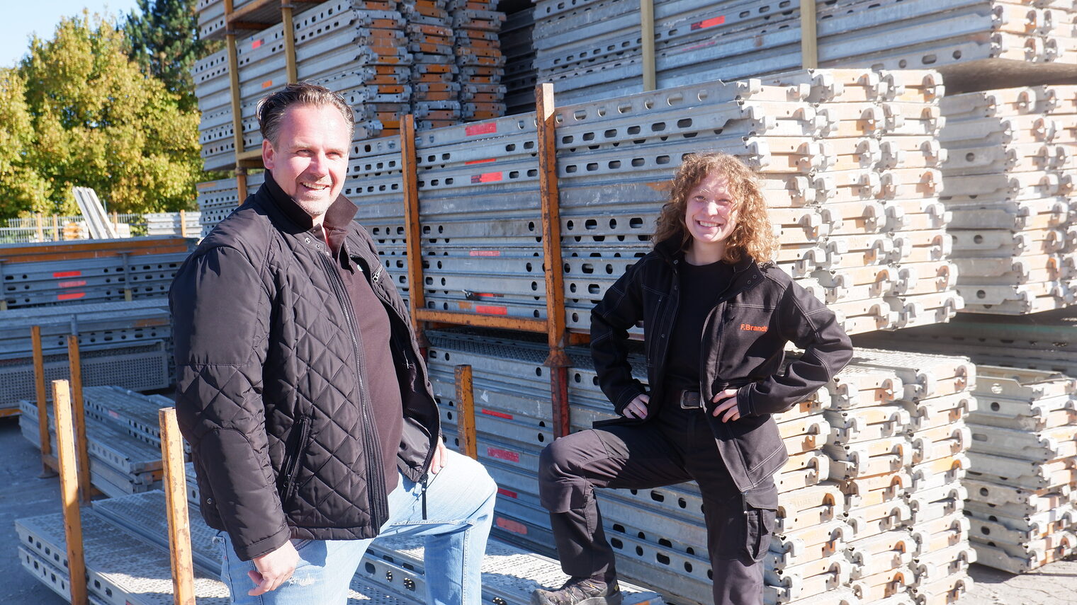 Ausbilder und Auszubildende stehen draußen vor einem 