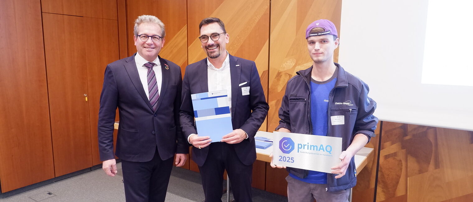 Zwei Vertreter von Elektro Rieger nehmen die Auszeichnung von Thomas Gehre entgegen.