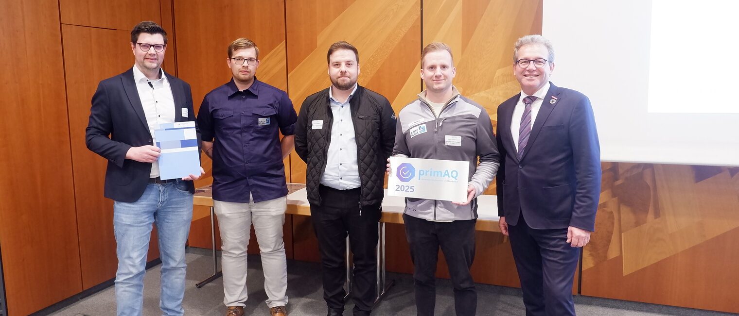 Der Chef und drei Mitarbeitende der Firma Kälte-Klima Bertuleit & Müller nehmen die Auszeichnung aus den Händen des Handwerkskammerpräsidenten entgegen.