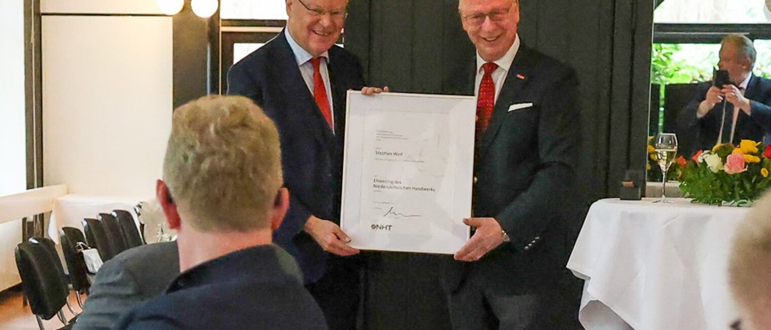 Ministerpräsident a.D. Stephan Weil und NHT-Präsident Mike Schneider mit einer Urkunde bei der Ehrung in einem festlichen Saal.