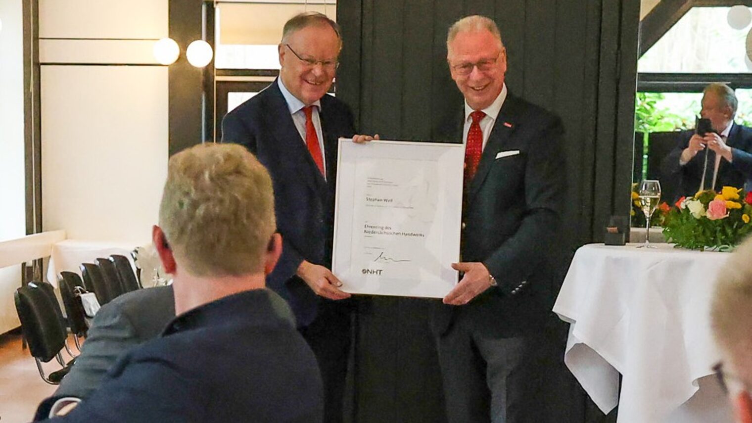 Ministerpräsident a.D. Stephan Weil und NHT-Präsident Mike Schneider mit einer Urkunde bei der Ehrung in einem festlichen Saal.
