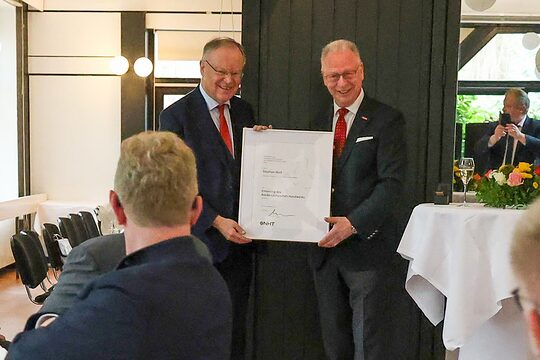 Ministerpräsident a.D. Stephan Weil und NHT-Präsident Mike Schneider mit einer Urkunde bei der Ehrung in einem festlichen Saal.