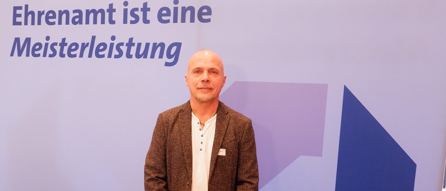 Andreas Güttlein steht vor einem Rollup Ehrenamt ist eine Meisterleistung.