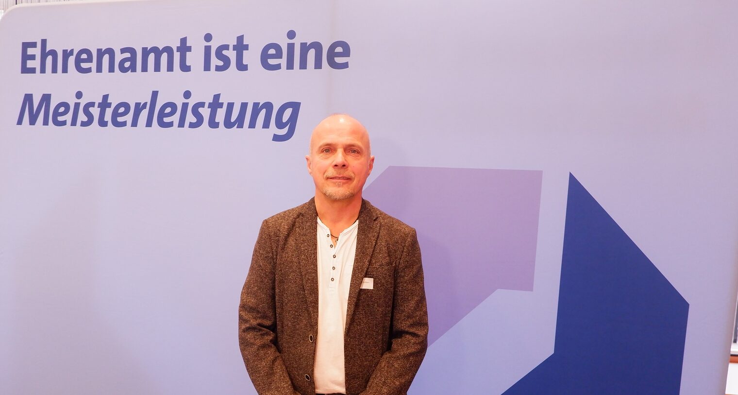 Andreas Güttlein steht vor einem Rollup Ehrenamt ist eine Meisterleistung.