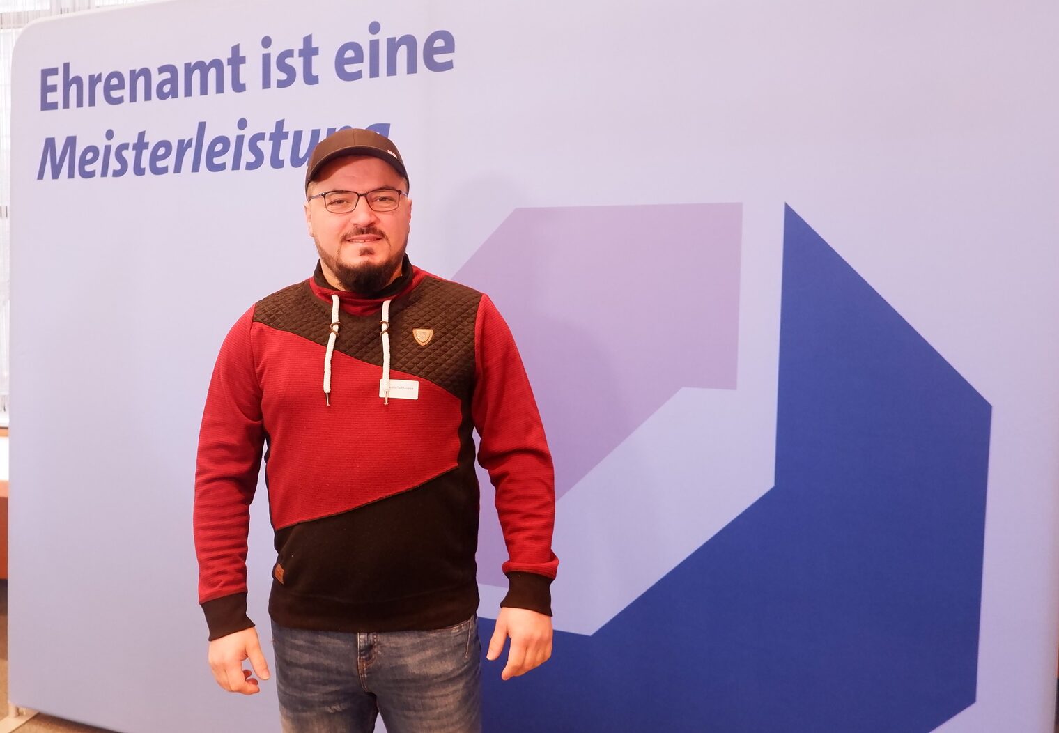 Mustafa Moussa vor einer Leinwand mit der Aufschrift: Ehrenamt ist Meisterleistung.