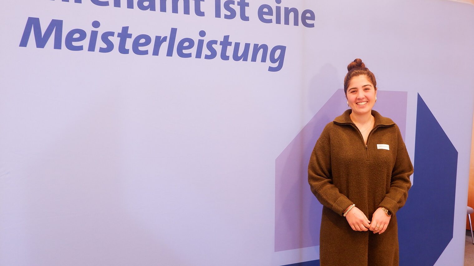 Zarah Javid Milani vor der Leinwand mit der Aufschrift "Ehrenamt ist eine Meisterleistung".