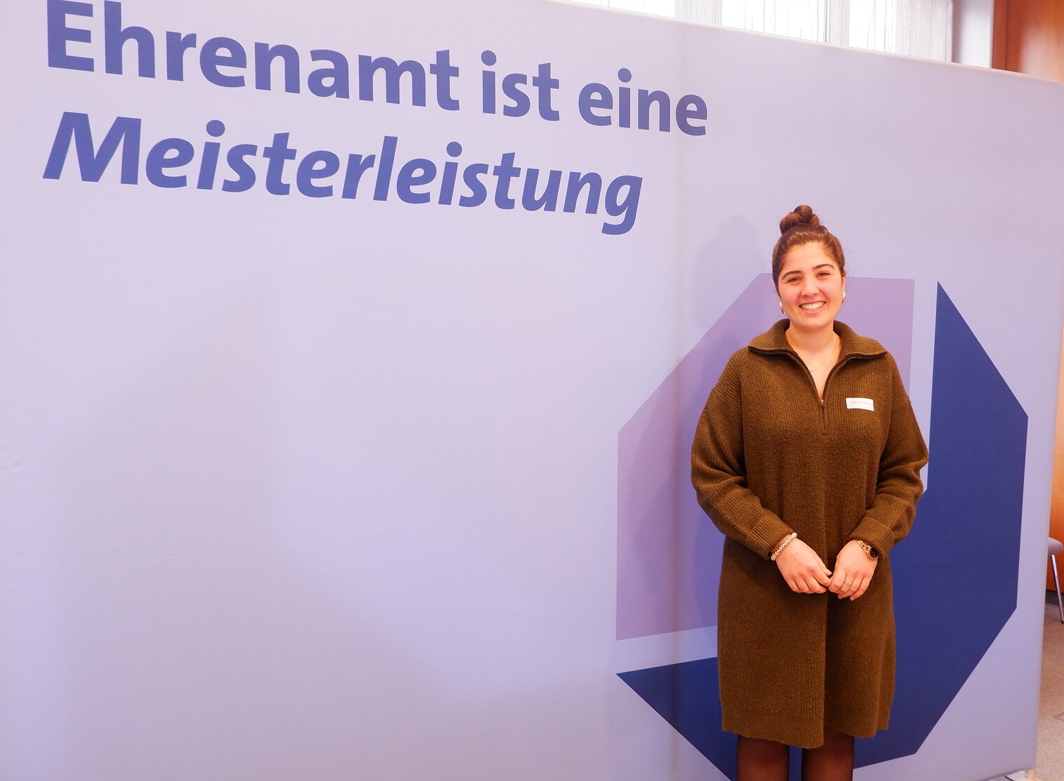 Zarah Javid Milani vor der Leinwand mit der Aufschrift "Ehrenamt ist eine Meisterleistung".