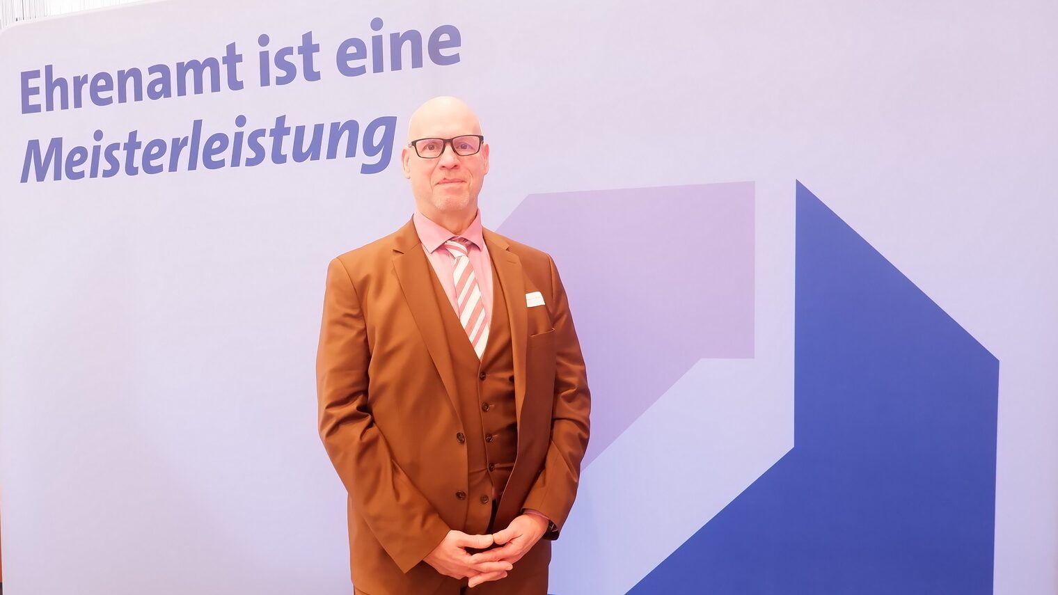 Frank-Joachim Weiß vor der Leinwand mit der Aufschrift Ehrenamt ist eine Meisterleistung