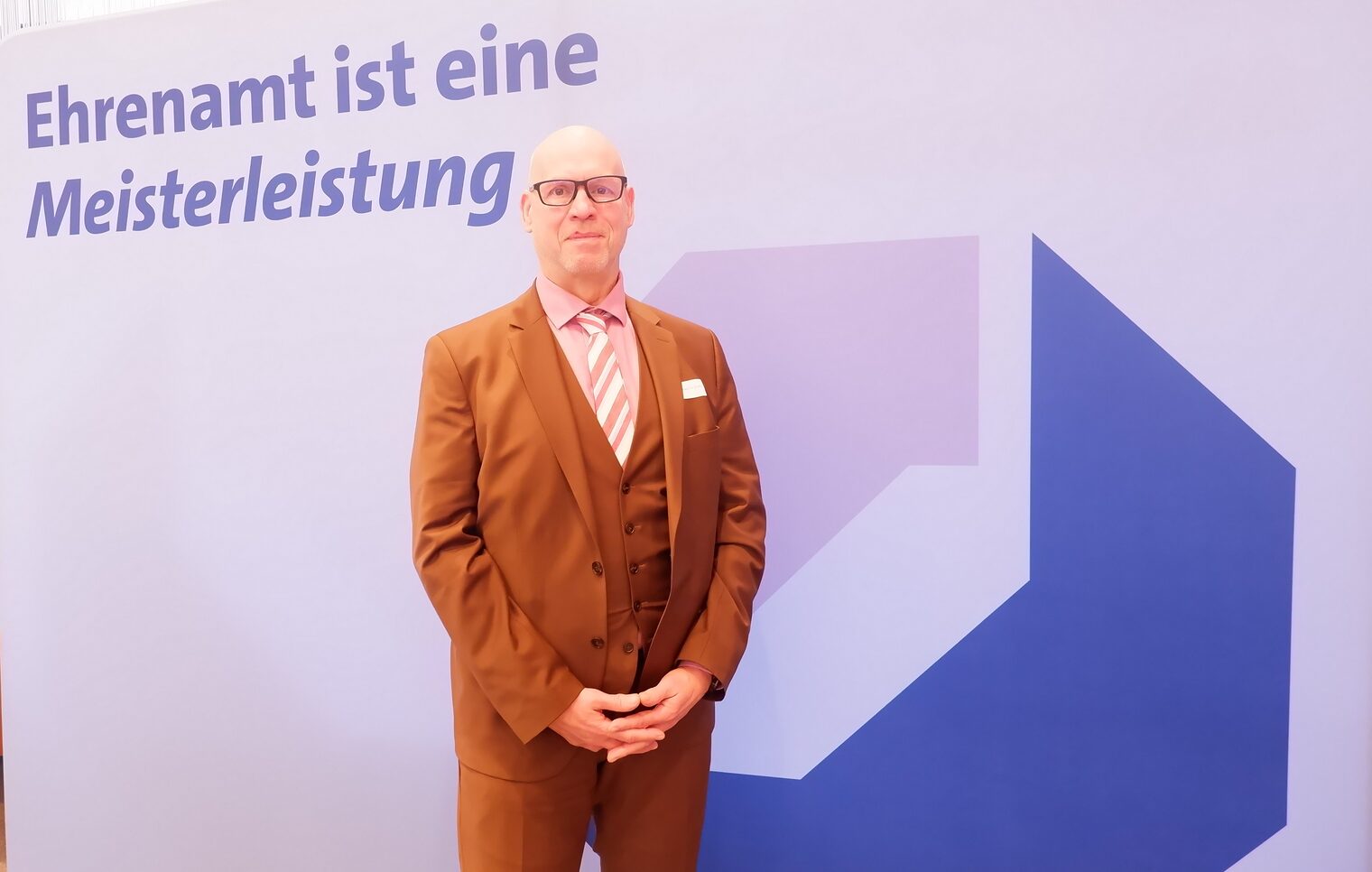 Frank-Joachim Weiß vor der Leinwand mit der Aufschrift Ehrenamt ist eine Meisterleistung