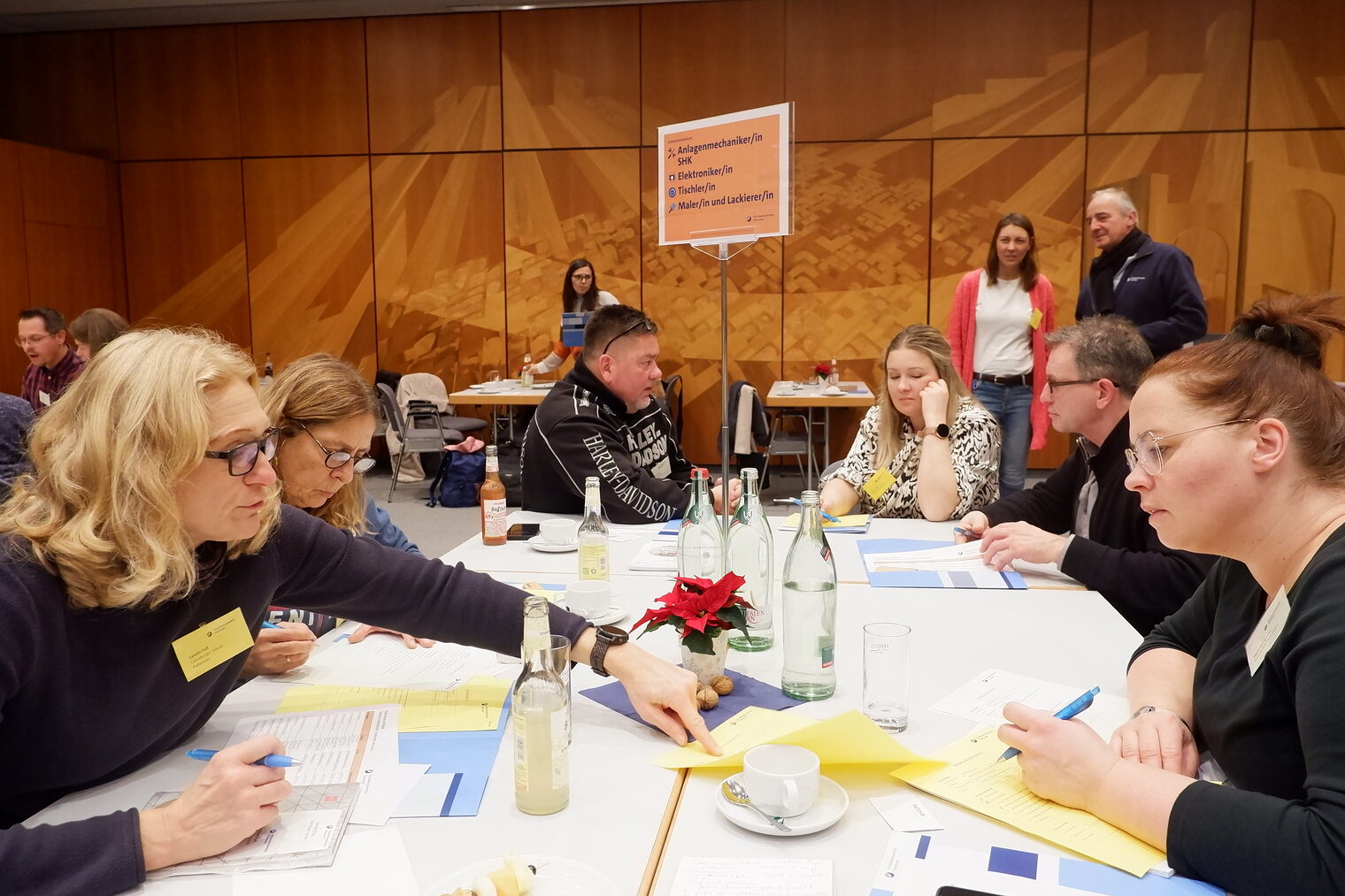 Sechs Menschen sitzen an einem Tisch und unterhalten sich.