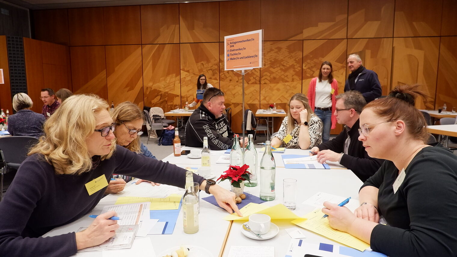 Sechs Menschen sitzen an einem Tisch und unterhalten sich.
