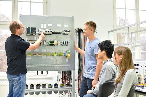 Jugendliche und Lehrer in der Berufsausbildung für Elektrotechnik.