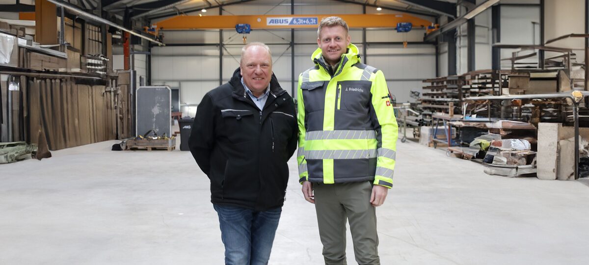 Jannes Friedrichs (re.) und Holger Bremer (li.) in der Halle Ihres Betriebs nebeneinander stehend.