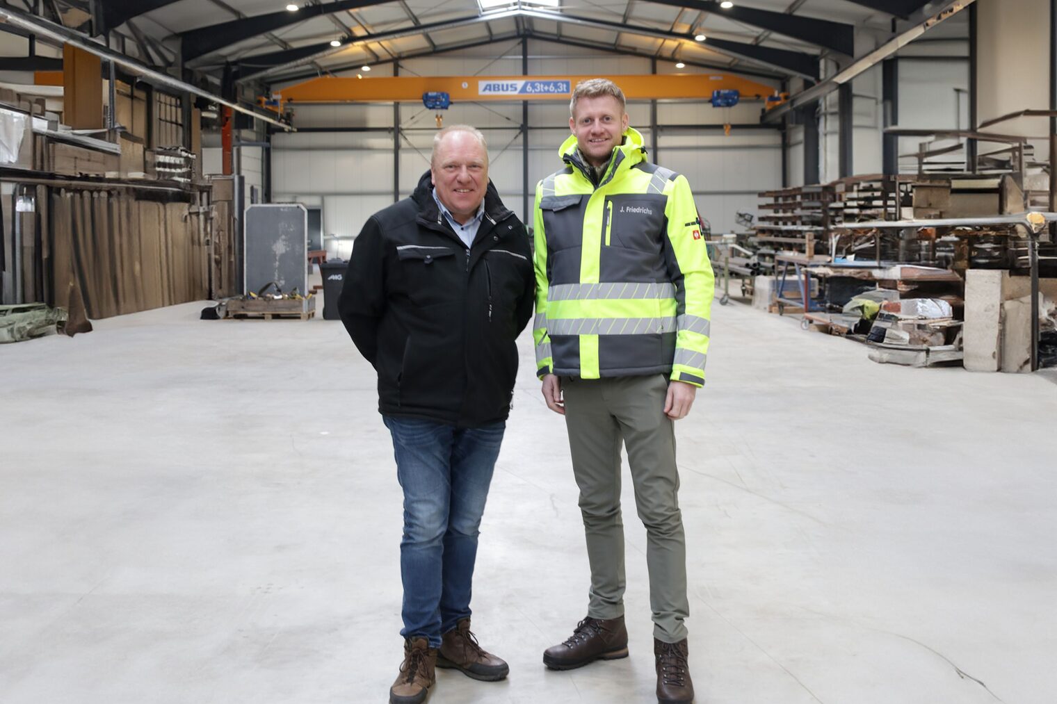 Jannes Friedrichs (re.) und Holger Bremer (li.) in der Halle Ihres Betriebs nebeneinander stehend.