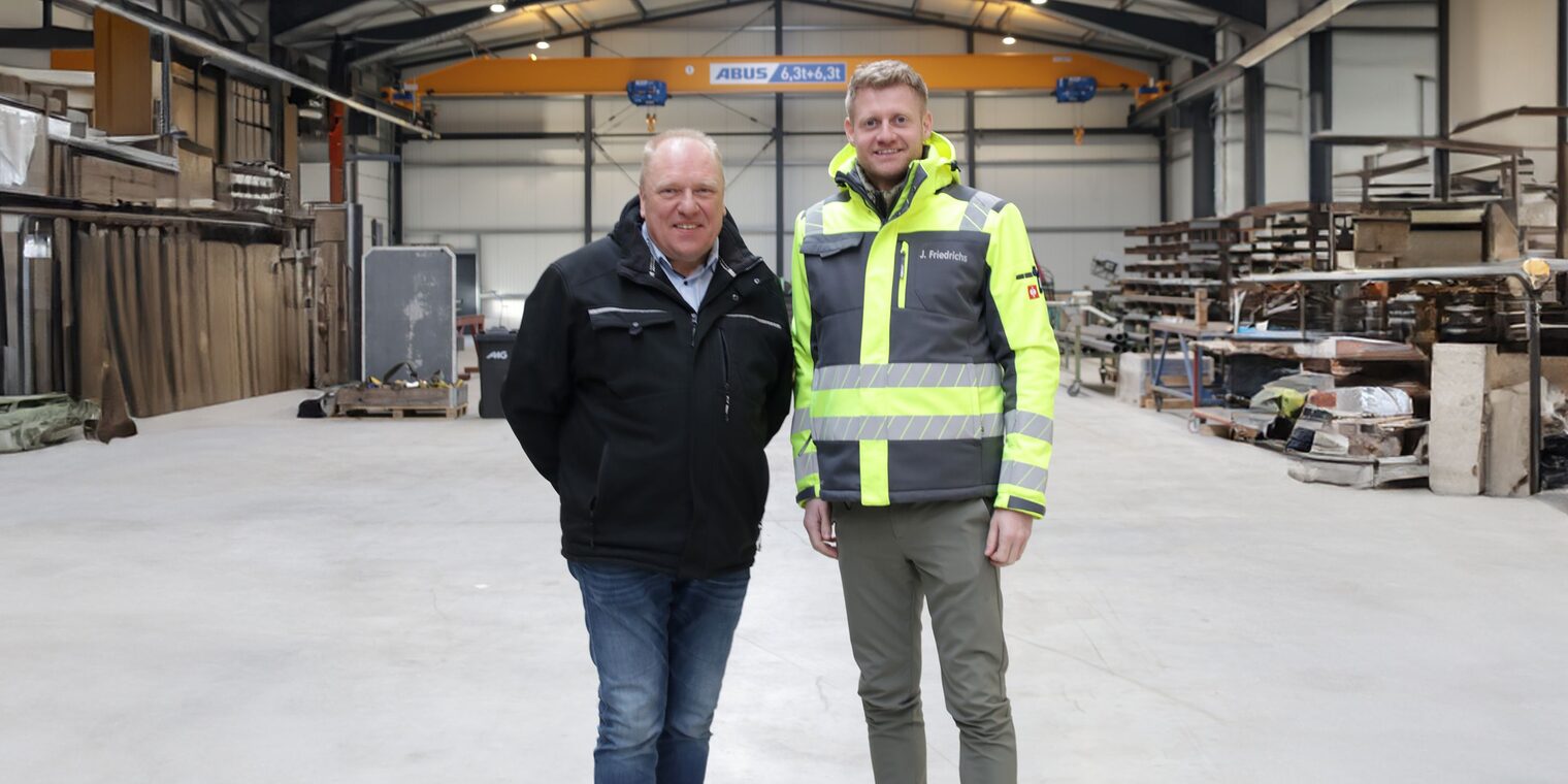 Jannes Friedrichs (re.) und Holger Bremer (li.) in der Halle Ihres Betriebs nebeneinander stehend.