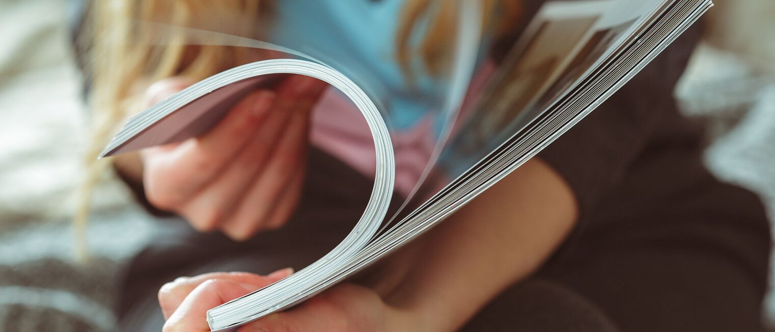 Hände einer Frau, die durch ein Magazun blättert.