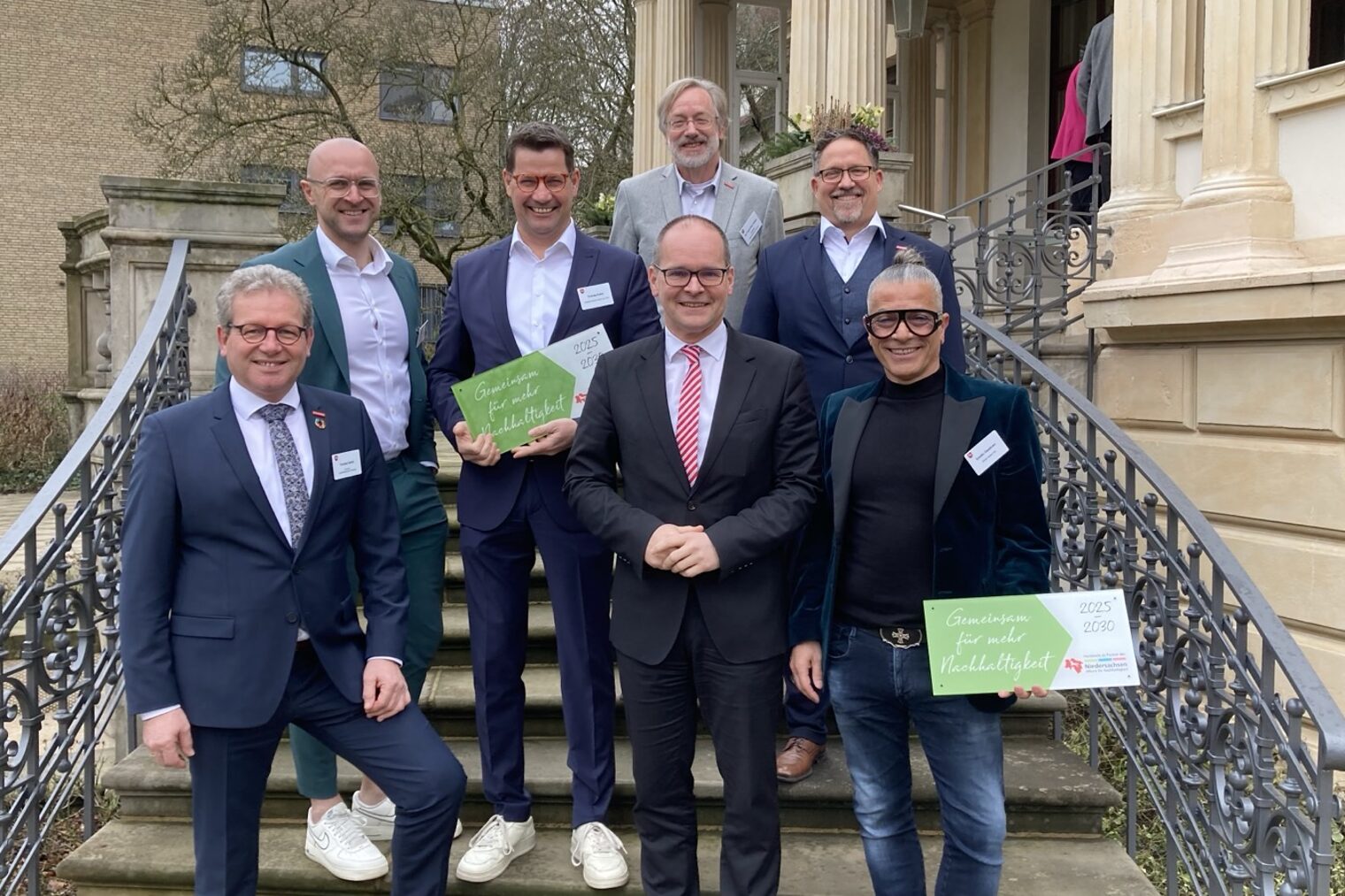 Die ausgezeichneten Betriebe mit Minister und Handwerkskammerpräsident und weiteren Personen stehen auf einer Treppe des Gästehauses der niedersächsischen Landesregierung.