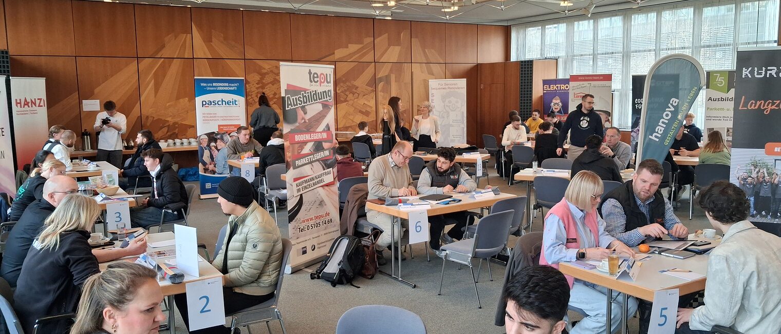 Jugendliche sitzen an vielen Tischen den Ausbildern der Handwerksbetriebe gegenüber.
