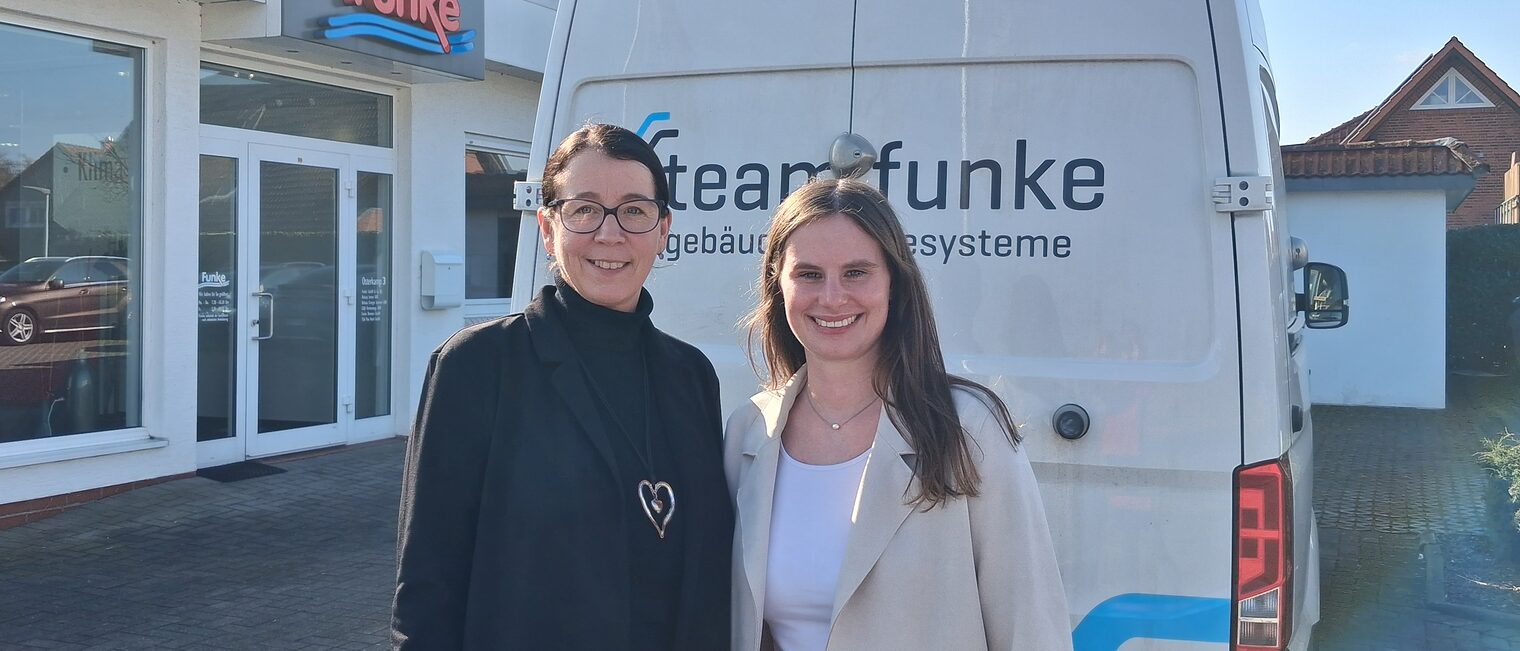 Marion Sievert und Hannah Diephaus stehen draußen vor einem Firmenwagen auf dem Hof von Team Funke. 
