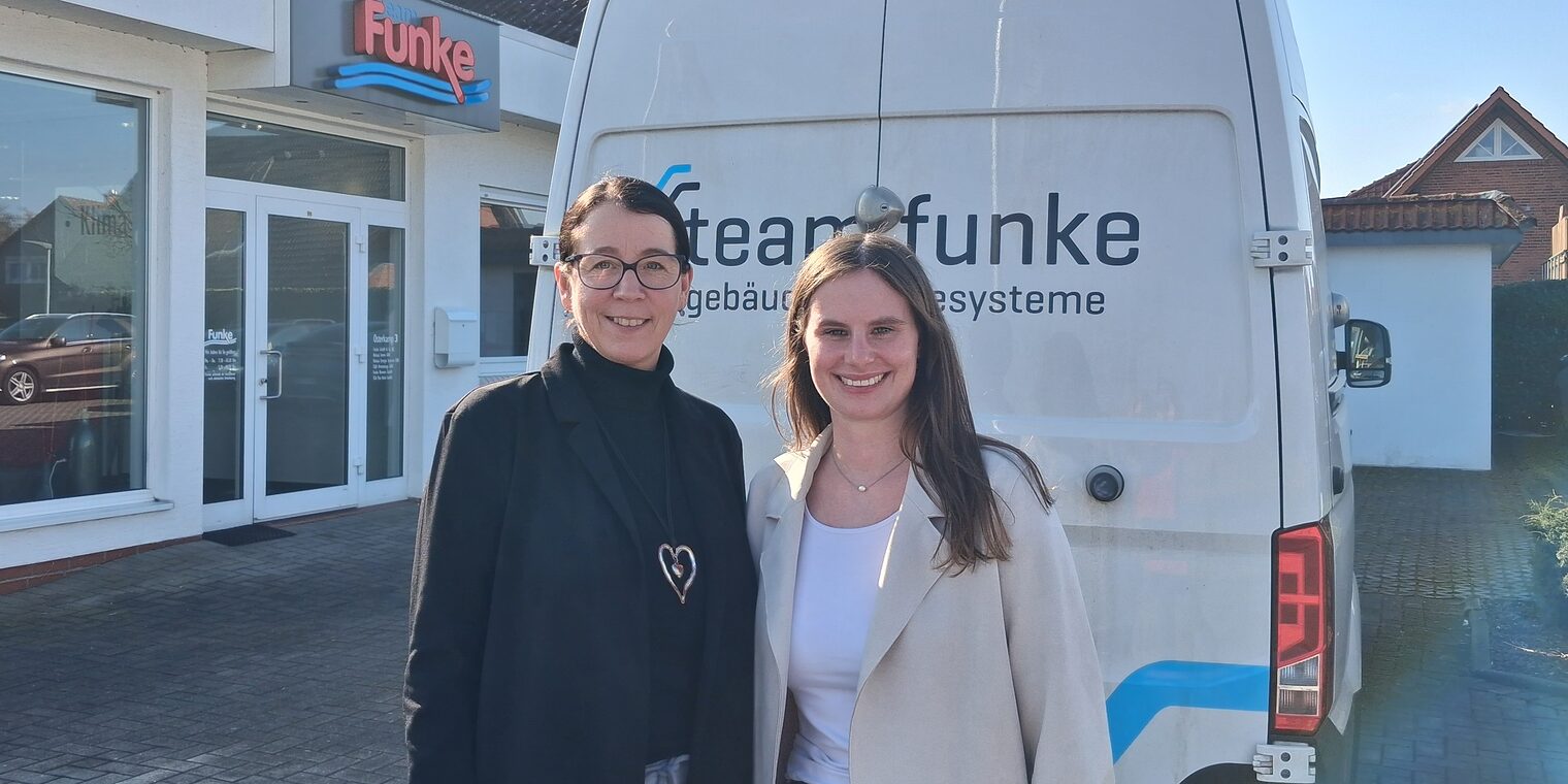 Marion Sievert und Hannah Diephaus stehen draußen vor einem Firmenwagen auf dem Hof von Team Funke. 