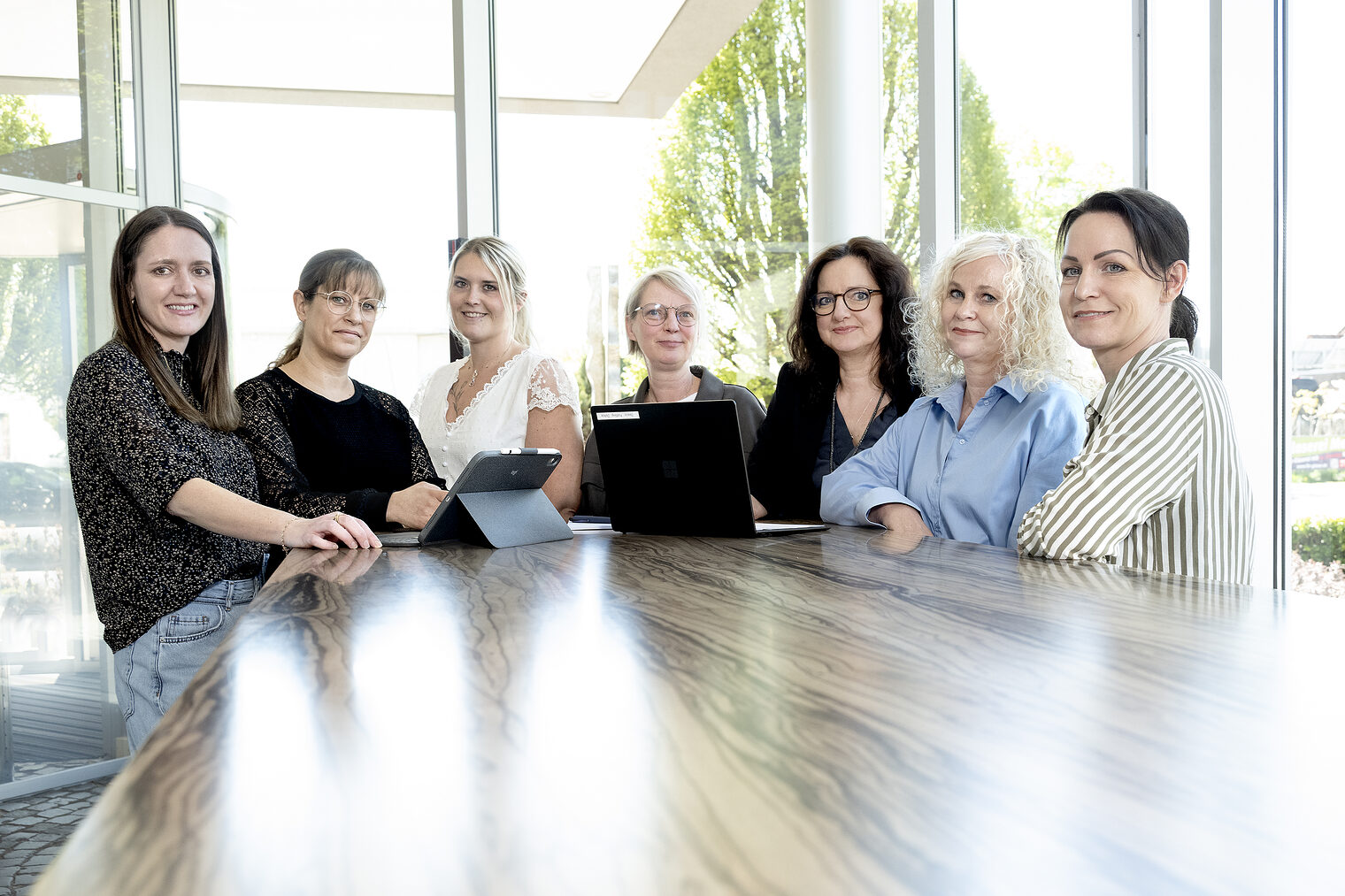 Sieben Frauen nebeneinander an einem Tisch.
