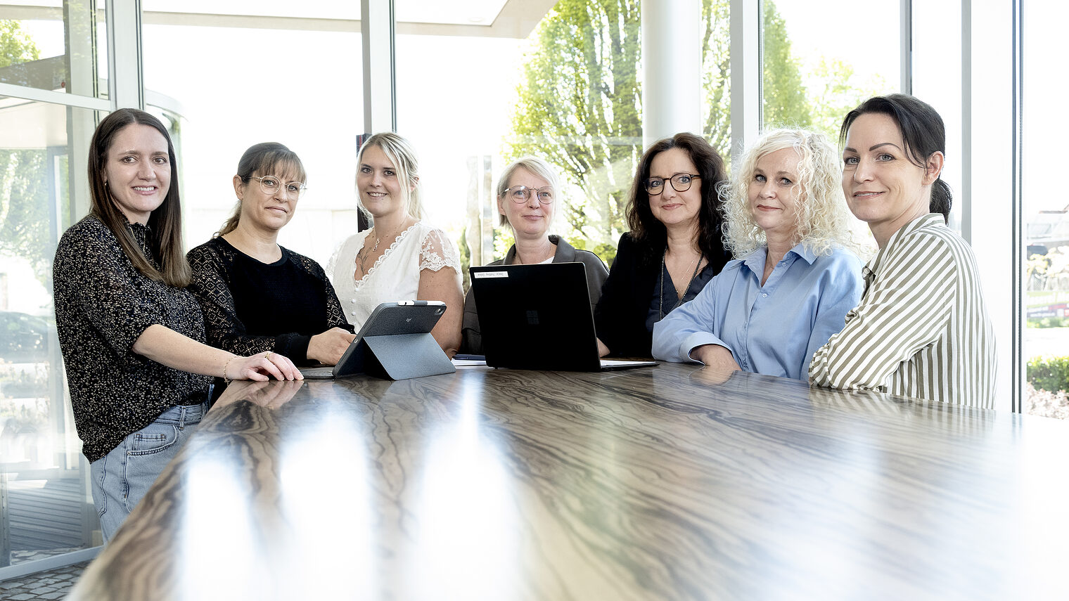 Sieben Frauen nebeneinander an einem Tisch.