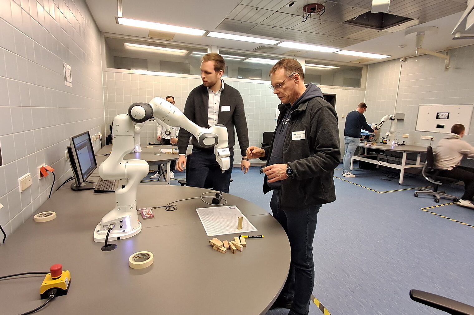 Zwei Männer betrachten Roboter auf einem Tisch