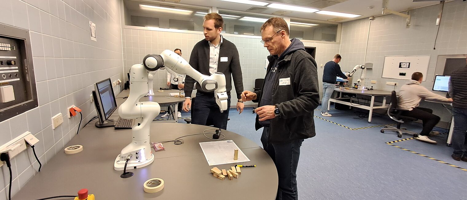 Zwei Männer betrachten Roboter auf einem Tisch
