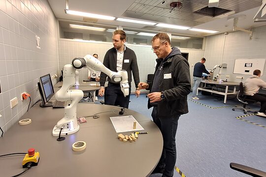 Zwei Männer betrachten Roboter auf einem Tisch