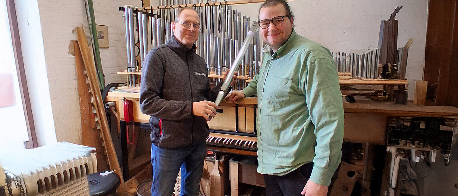 Orgelbauermeister Georg Schloetmann und Azubi Georg Blendermann inb der Werkstatt vor einer Orgel.