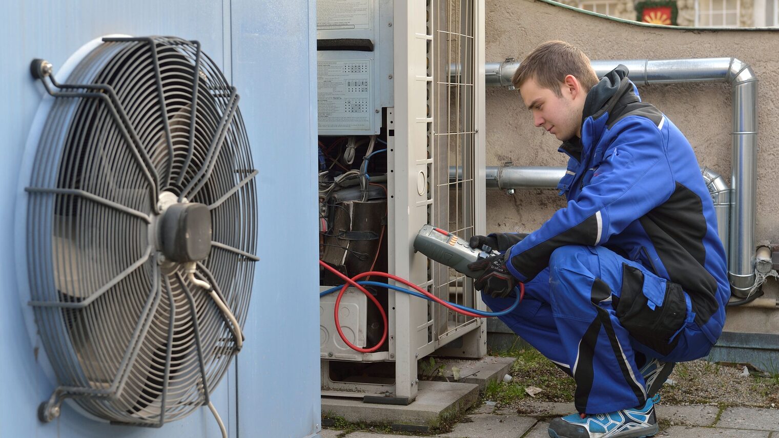 Mechatroniker für Kältetechnik misst Werte bei einer Wärmepumpe.