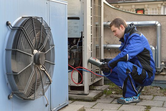 Mechatroniker für Kältetechnik misst Werte bei einer Wärmepumpe.