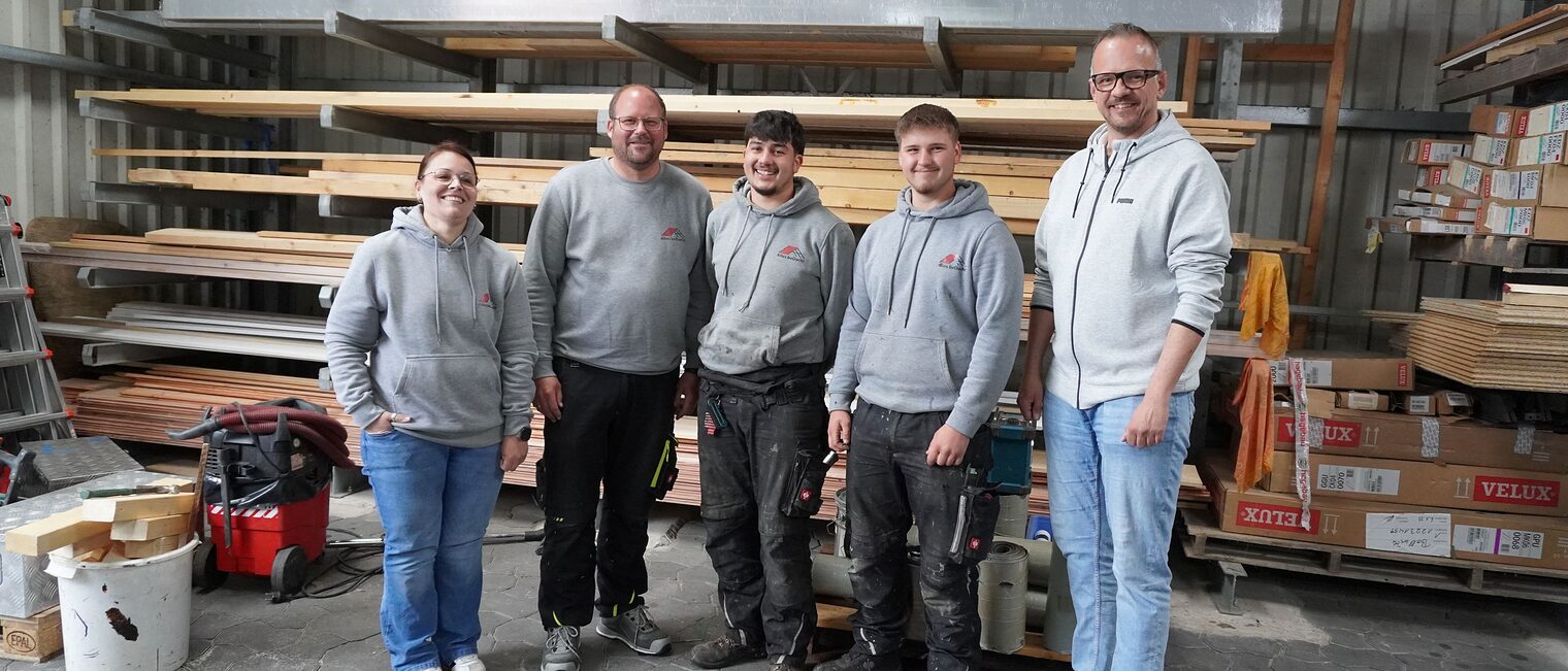 Team der Dachdeckerei alles beDacht mit Ausbildungsberater Christian Bunzel stehen zusammen in der Bauhalle.