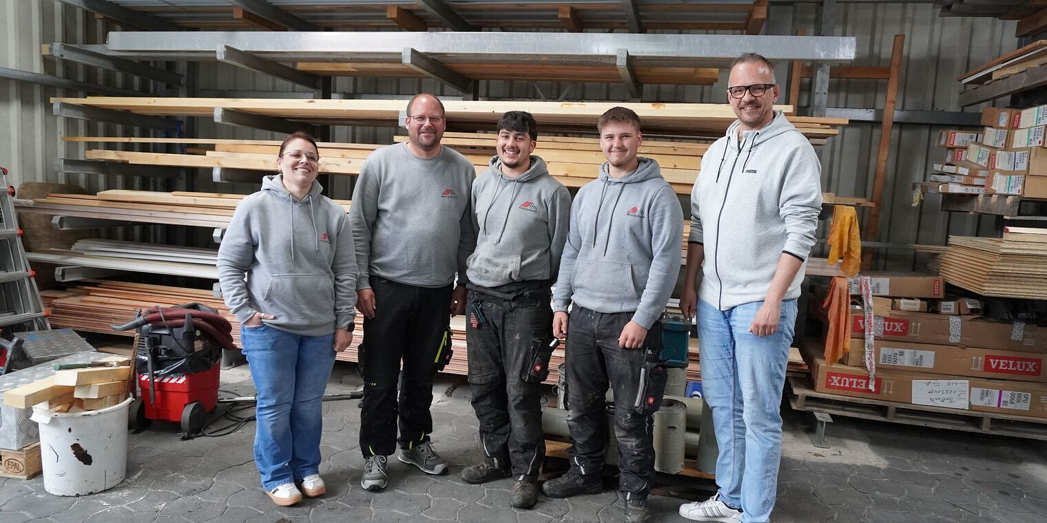 Team der Dachdeckerei alles beDacht mit Ausbildungsberater Christian Bunzel stehen zusammen in der Bauhalle.