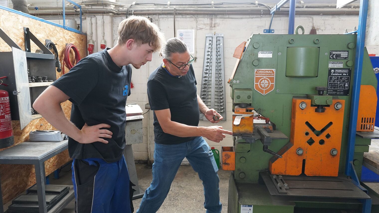 Ausbilder Uwe Wecke und Julius Caspar, Auszubildender zum Metallbauer, in der Ausbildungswerkstatt an einer Maschine.