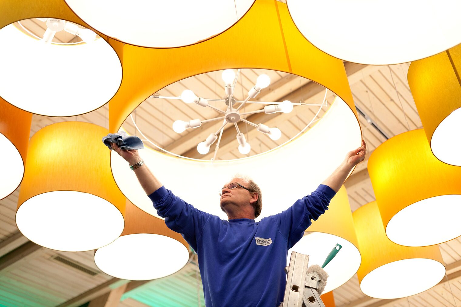 Gebäudereiniger reinigt Deckenlampe.