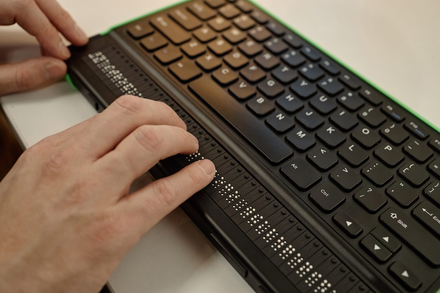 Person, die Braille-Schrift auf einer Tastatur liest.