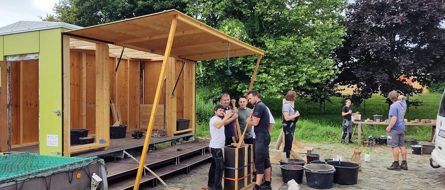 Menschen in der Gruppe auf einem außengelände, die sich Holz anschauen.
