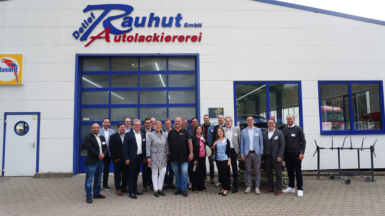 Gruppe steht vor einem großen Hallenstor der Autolackierer Rauhut.