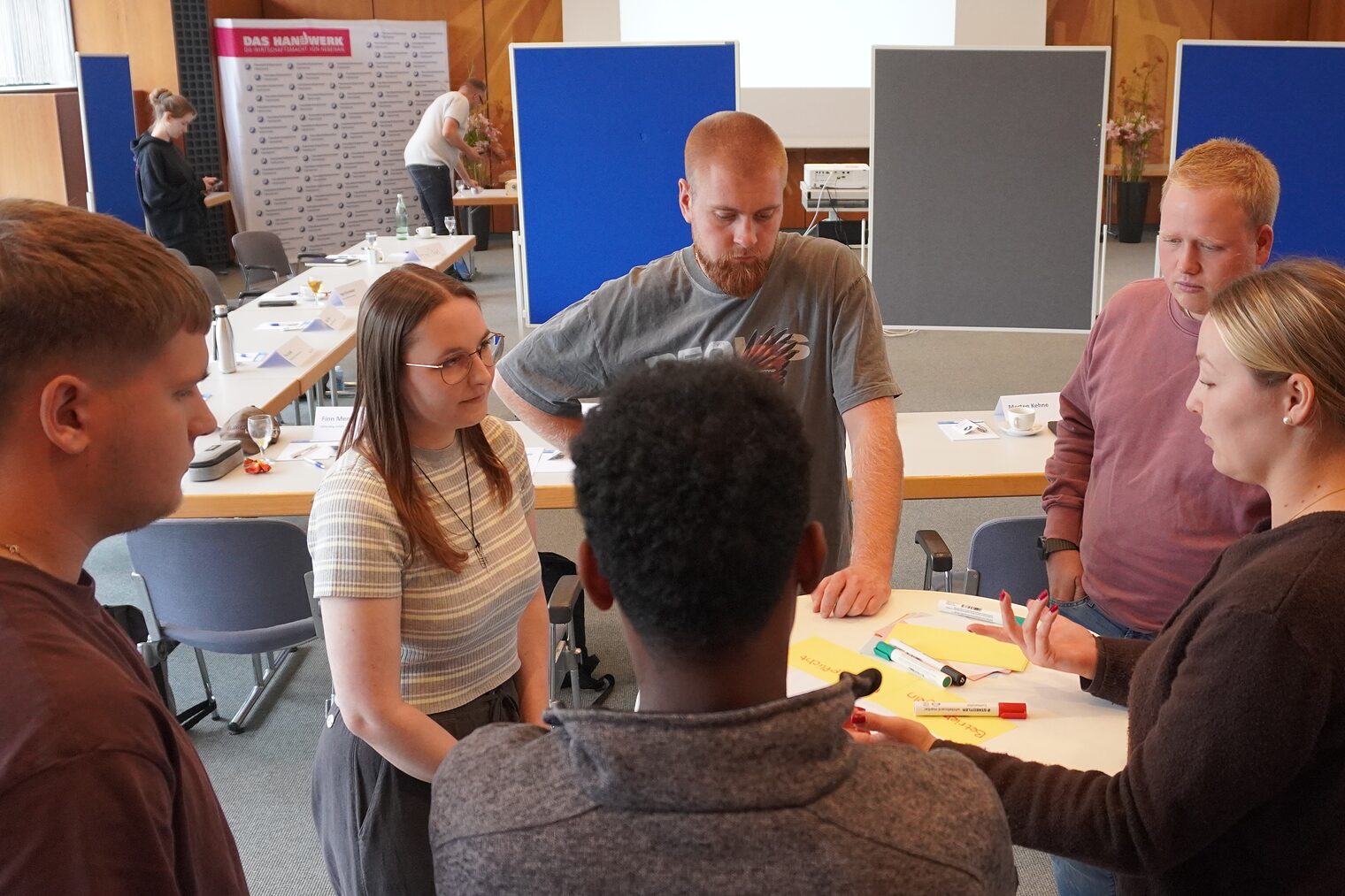 Gruppe von Gesellen beim Workshop am Tisch bei Gruppenaufgabe.