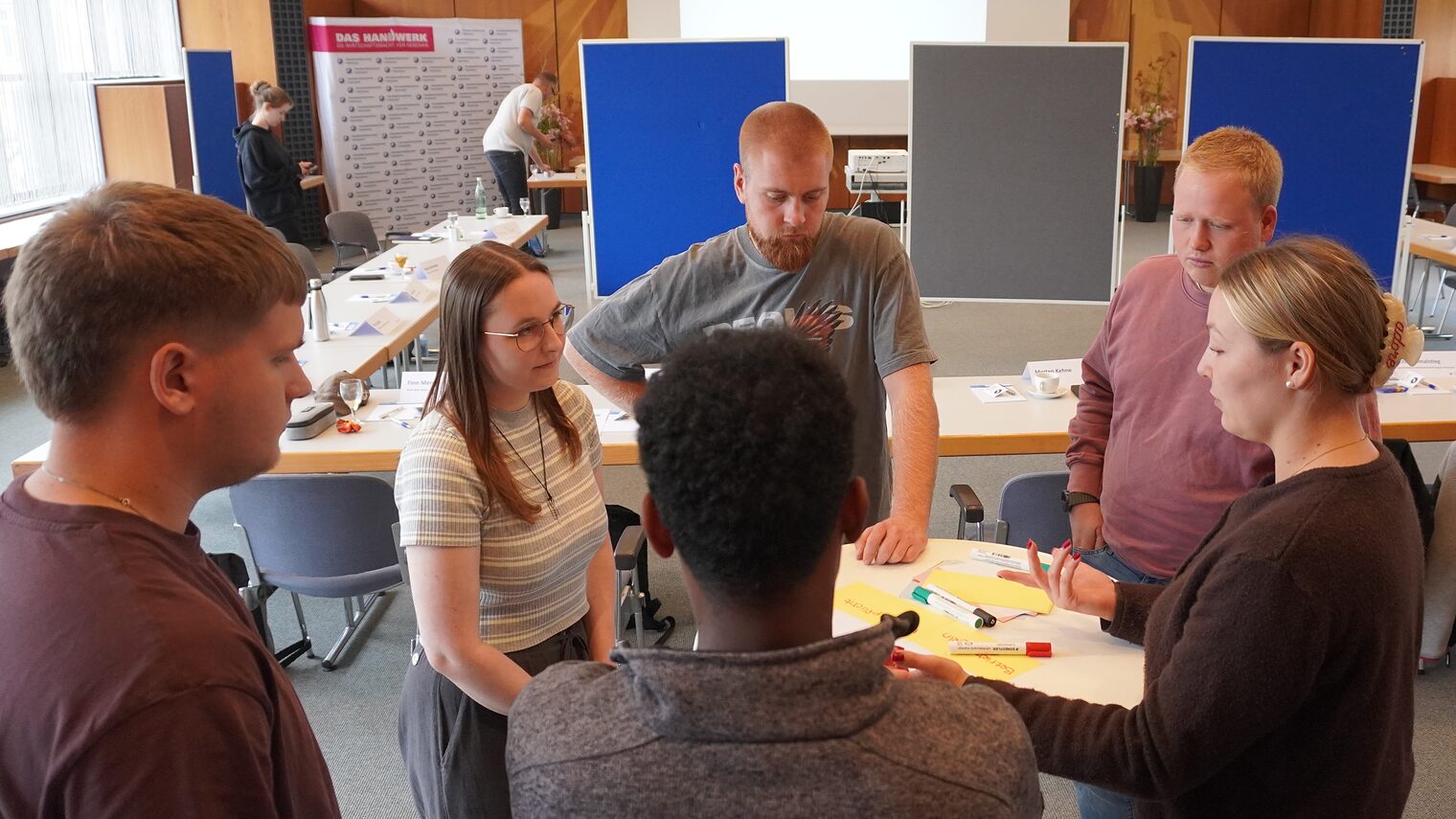 Gruppe von Gesellen beim Workshop am Tisch bei Gruppenaufgabe.