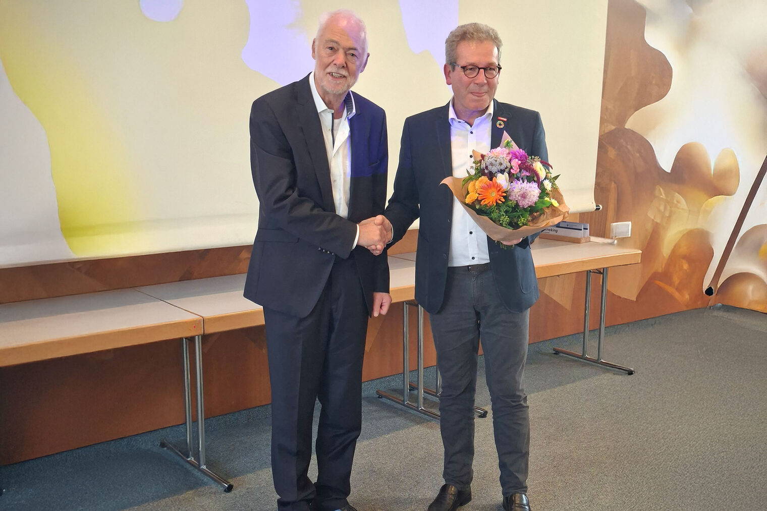 Thomas Gehre überreicht Herrn Wenzel einen Blumenstrauß.